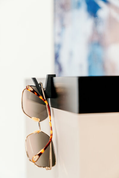 Sonnenbrille hängt an einem Universalhaken, der auf der Abdeckwanne eines Schrankes aufgesteckt ist