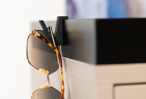 Sonnenbrille hängt an einem Universalhaken, der auf der Abdeckwanne eines Schrankes aufgesteckt ist.